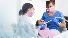 Zahnärztliche Chirurgie - Ärztin und zahnmedizinische Fachangestellte behandeln Patientin