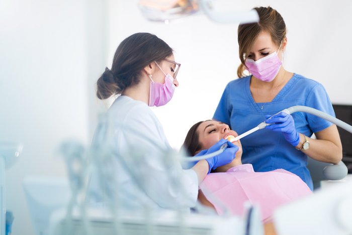 Zahnärztliche Chirurgie - Ärztin und zahnmedizinische Fachangestellte behandeln Patientin